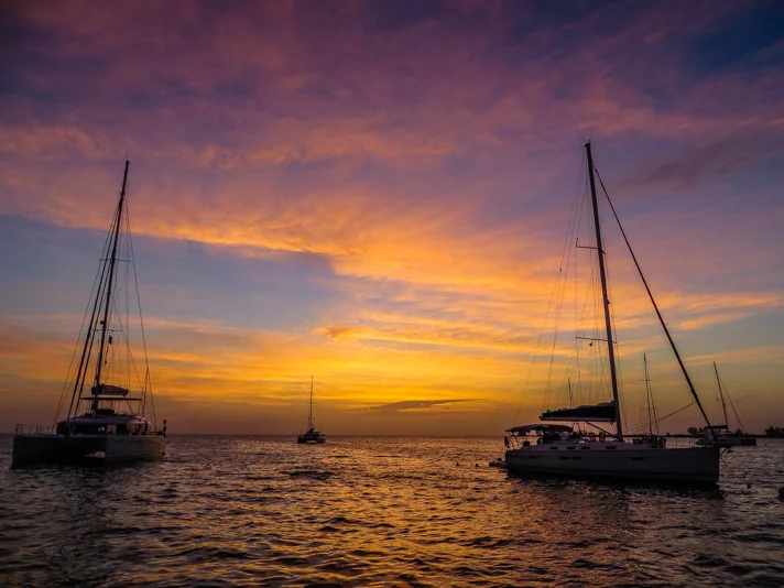 Sailing boats at anchor under a vivid golden and pink evening sky